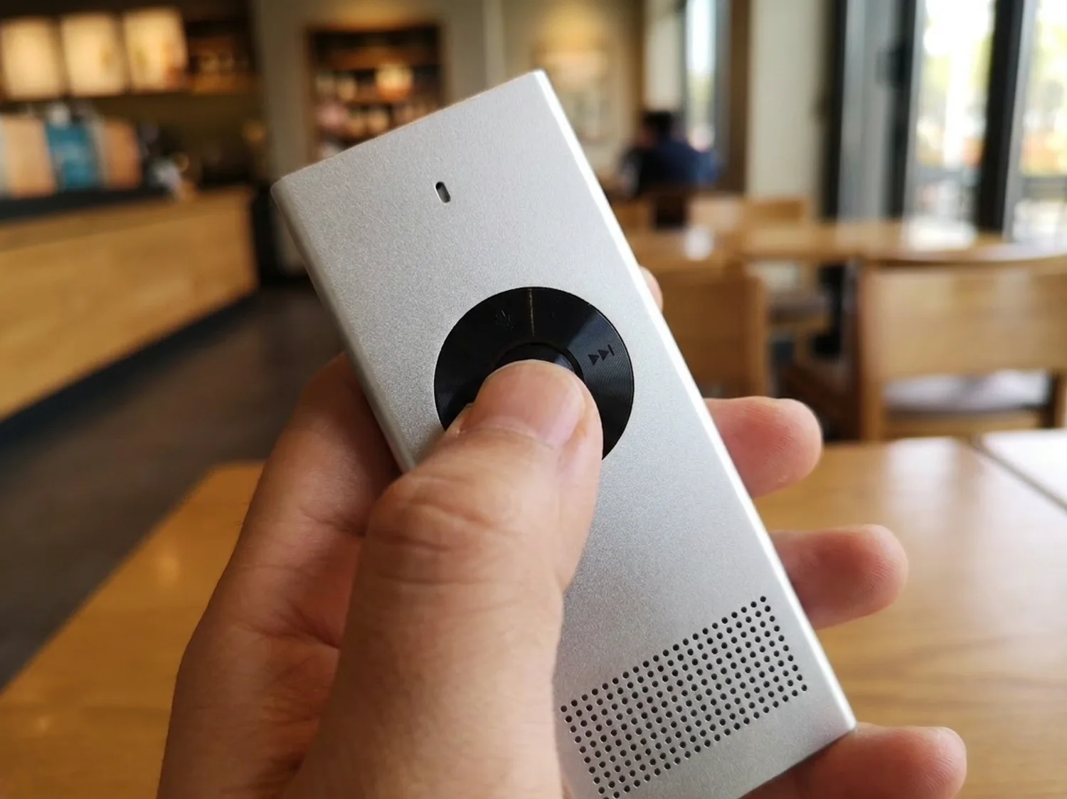 Close-up of the translator's round button and speaker grille, a finger pressing the button